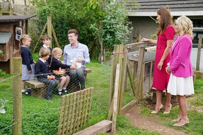 Kate Middleton y Jill Biden conversan con un grupo de niños mientras estos alimentan a los conejos.