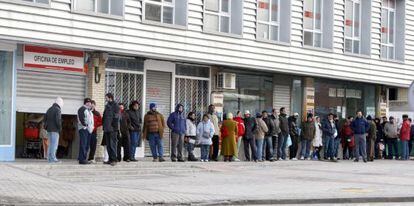 Varias personas forman cola ante una oficina de empleo.