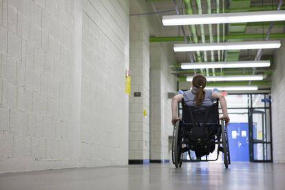 Una mujer en silla de ruedas en el pasillo de una institución educativa