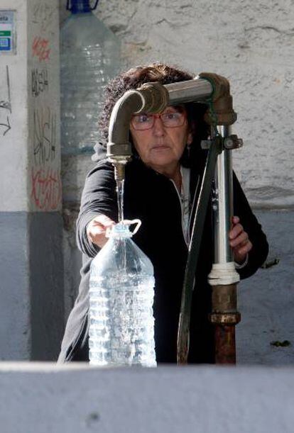 Una vecina de Vigo se abastece de agua potable en una fuente pública.