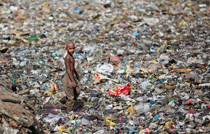 Un niño camina sobre una montaña de basura que tapa un desagüe en Nueva Delhi, India.