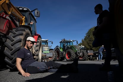 Un agricultor descansa apoyado en su tractor en la AP-7, donde alrededor de 200 payeses siguen instalados tras 24 horas del corte iniciado el martes.