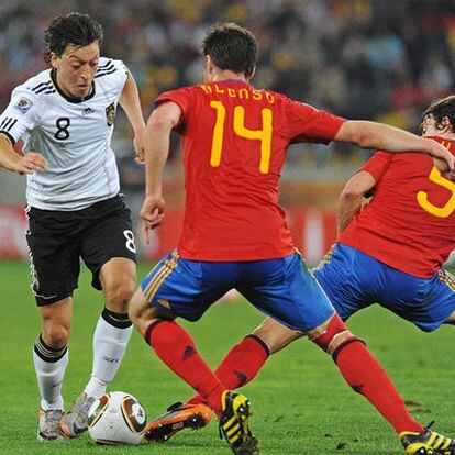 Özil trata de eludir a Alonso y Puyol durante el partido entre España y Alemania en el Mundial.
