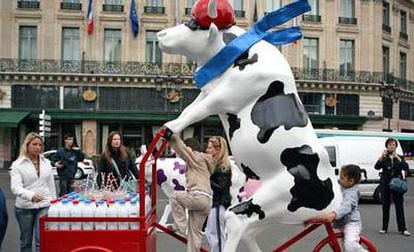 Unos niños juegan con la escultura de una vaca creada por el artista francés Diotalevi en París.