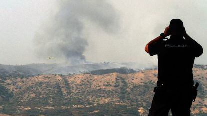 Un policía observa el incendio de Cerro Muriano.