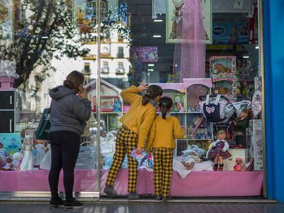 Dos menores miran el escaparate de una tienda de juguetes en Sevilla.