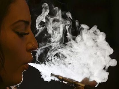 Una mujer exhala el vapor de un cigarrillo electrónico.