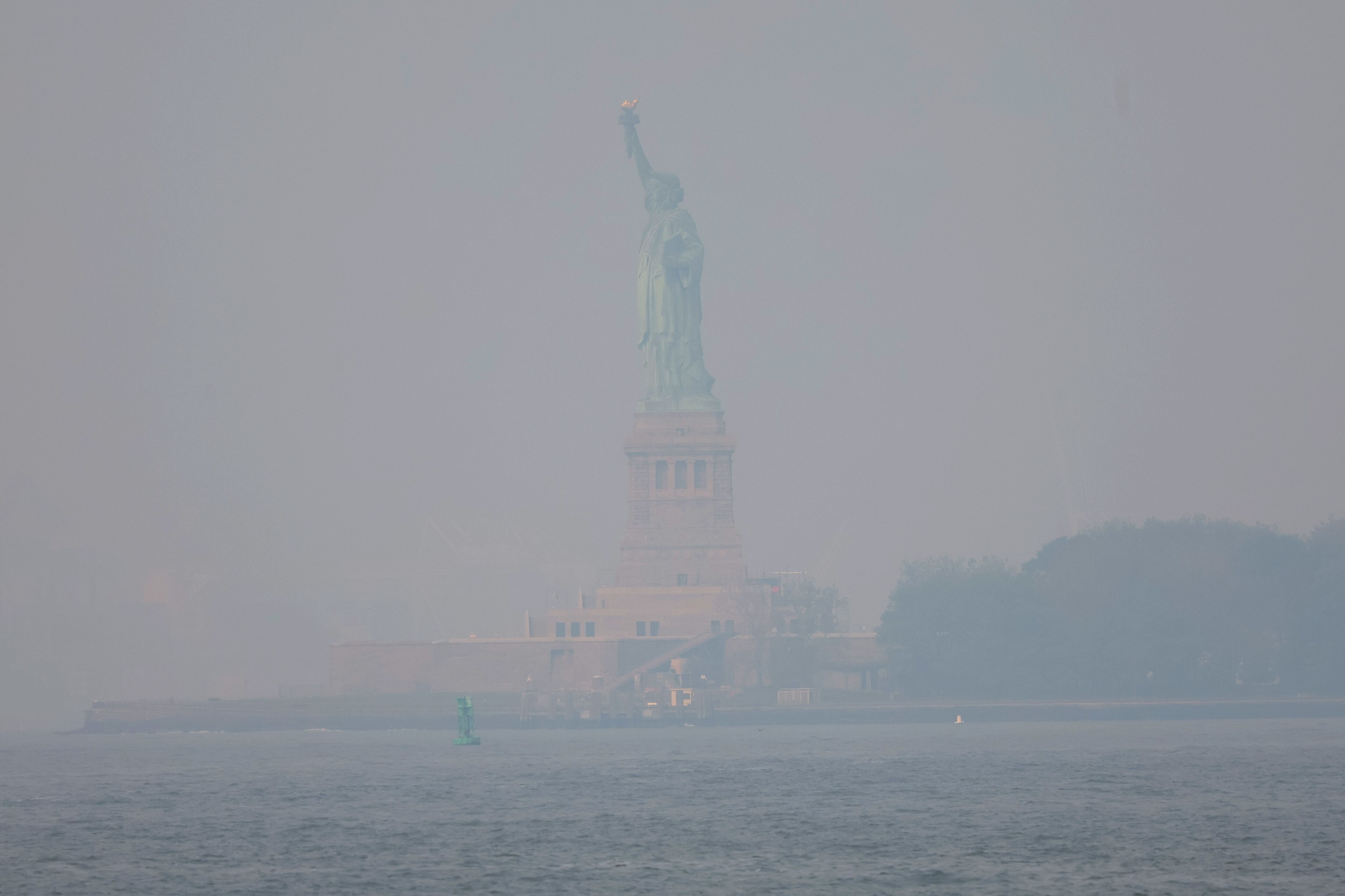 El humo de los incendios forestales canadienses cubren la Estatua de la Libertad, este jueves.