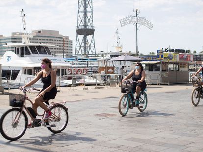 Varias turistas pasean en bicicleta por el puerto de Barcelona.