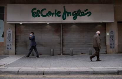 Dos personas pasan delante de la entrada de El Corte Inglés de Linares, en Jaén, el pasado 5 de marzo.