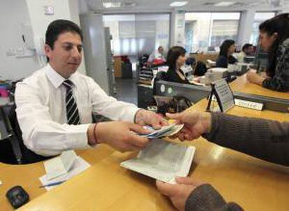 Un empleado de una sucursal del Banco Laiki entrega el dinero retirado por uno de sus clientes en Nicosia (Chipre).