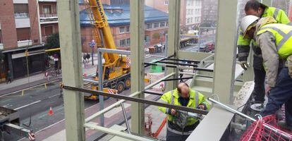 Varios operarios trabajan en la instalación de la nueva escalera de la plaza de abastos de Vitoria. 