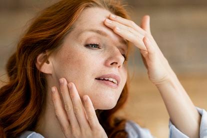 Portrait of redheaded woman touching her face