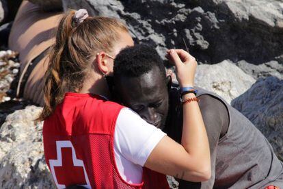 Una trabajadora de la Cruz Roja y un migrante que ha logrado cruzar uno de los espigones fronterizos de Ceuta este martes se abrazan.
