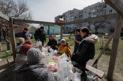 Lugareños almuerzan fuera de un edificio residencial dañado en Makariv, cerca de Kiev, el pasado 14 de abril. 