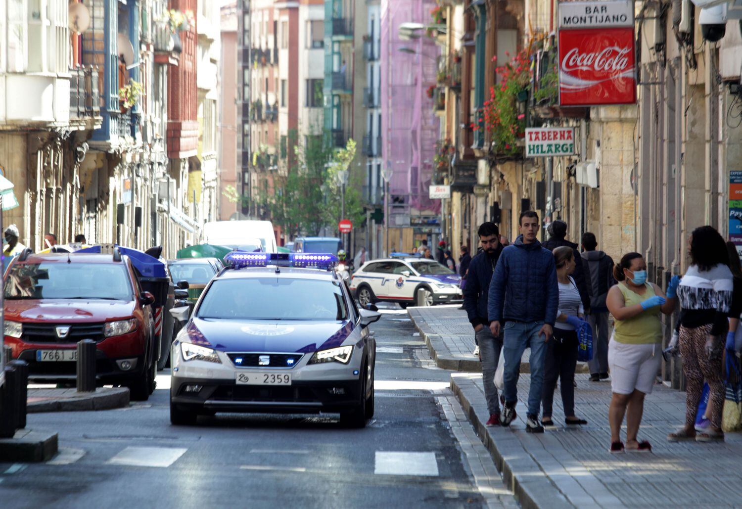 Dos coches policiales patrullan la calle de San Francisco de Bilbao este jueves.