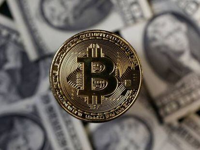 Un bitcoin junto a billetes de dólar.