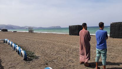 Los hermanos Usama y Mohamed, en una playa de la bahía de Alhucemas desde donde partió su hermano menor, Marwan, hacia España. Al fondo se encuentra el peñón de Alhucemas, con una base militar española.