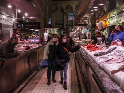 Dos personas pasan por un puesto de pescado en el Mercado Central de Valencia.