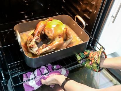 Una persona saca un pavo cocinado del horno.