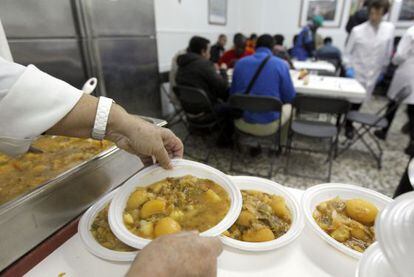 Voluntarios del comedor Cuatro Caminos, en Madrid, sirven comidas.