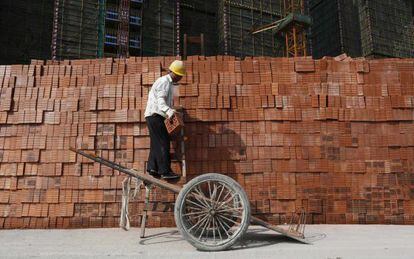 Un obrero apila ladrillos para un edificio en construcci&oacute;n en Hangzhou, en la provincia china de Zhejiang.