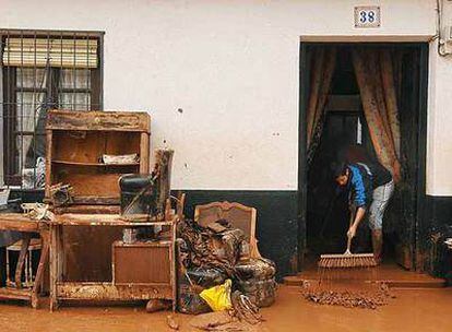 Un hombre retira el agua y el barro que han entrado en su casa a causa de las lluvias en Villarrubia de los Ojos (Ciudad Real).