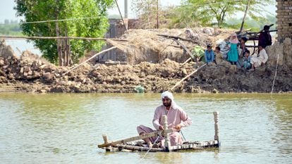 Un hombre afectado por las inundaciones utiliza una balsa improvisada para cruzar una corriente de agua cerca de su casa dañada en Jaffarabad, provincia de Baluchistán, en Pakistán, el 23 de septiembre de 2022.