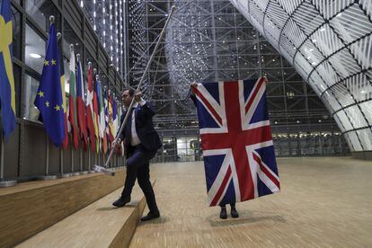 Dos funcionarios retiran la bandera de Reino Unido del interior del Consejo Europeo de Bruselas. 
