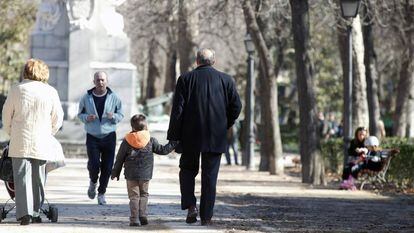 Unos abuelos pasean con su nieto por el parque.