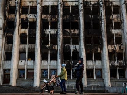 Una familia pasa ante el edificio quemado del Ayuntamiento de la ciudad kazaja de Almaty, en la plaza de la República.