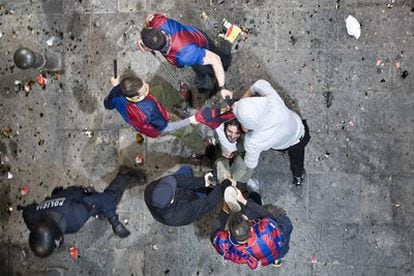 La alegría de la ciudad de Barcelona por el título liguero del Barça se ha visto empañada por unos aficionados violentos que han protagonizado una serie de disturbios en la zona de las Ramblas. En la imagen, varios agentes vestidos con la camiseta del Barcelona reducen a un hombre durante los disturbios.