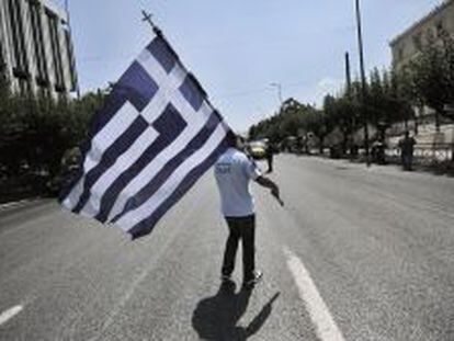 Un polic&iacute;a municipal griego sujeta una bandera nacional, en una protesta frente al Parlamento de Atenas, el pasado julio. 