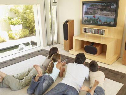 Una familia ve una película en el salón de casa.