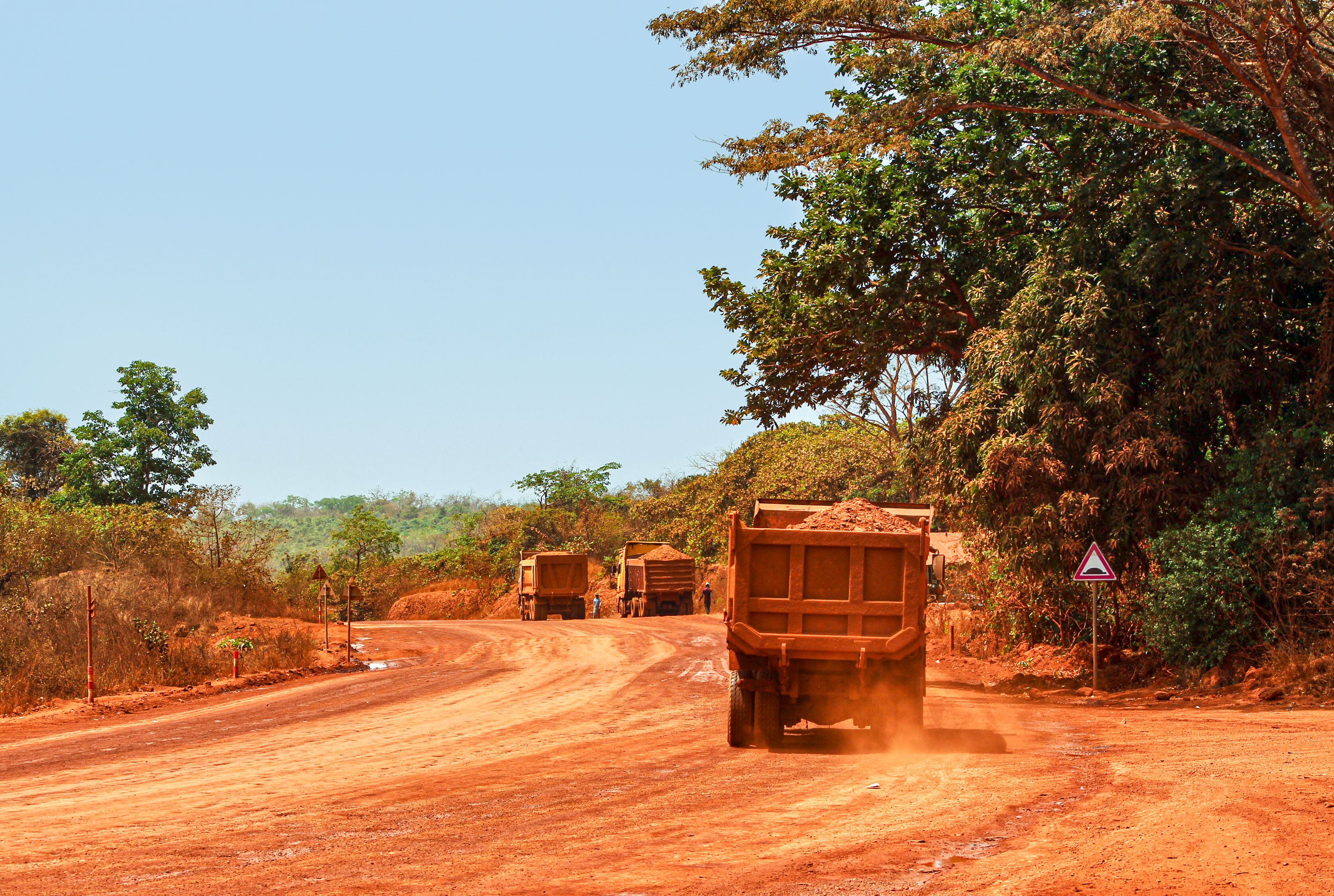 Varios camiones transportan bauxita por un camino en Guinea. En este país, el 83% de sus 23.000 chimpancés viven en zonas de interés minero.
