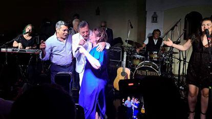 Jorge Olivera abraza a un músico y a su esposa durante una fiesta por el aniversario matrimonial de los dos.