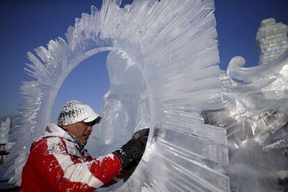 Un trabajador pule una de las esculturas de la ciudad de hielo en Harbin.