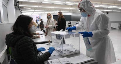 Un trabajador desinfecta una urna electoral en un colegio de Barcelona.