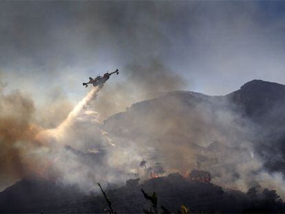 Un avión descargaba ayer agua sobre una pinada en llamas, en el término de Xeraco.