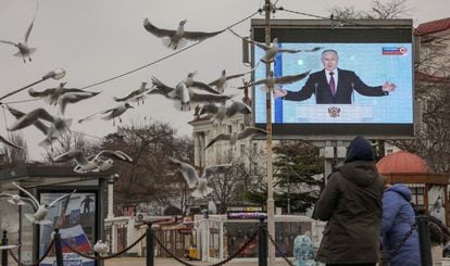 Dos personas frente a una pantalla gigante en la que se proyecta el discurso de Putin, este martes en Sebastopol, en la península de Crimea.