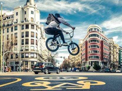 Un hombre tranquilo vuela sobre una bicicleta por las calles de Madrid