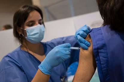 Una sanitaria procede a la vacunación de una mujer en el centro instalado en el Estadio Olímpico de Sevilla el 20 de mayo.