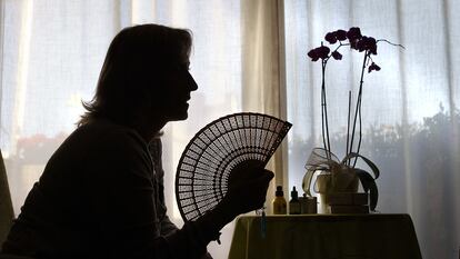 Una mujer alivia los calores de la menopausia con un abanico.