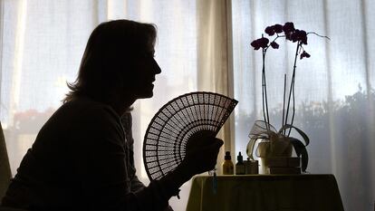 Una mujer alivia los calores de la menopausia con un abanico.