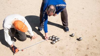 Dos jugadores miden la distancia entre el boliche y las bolas para comprobar cuál es la ganadora, en el parque de Aluche.