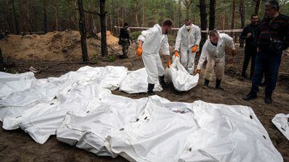 Las primeras exhumaciones muestran que las víctimas murieron por disparos, fuego de artillería o explosiones de minas. En la imagen, técnicos forenses sacaban un cadáver de una fosa en Izium, el jueves.