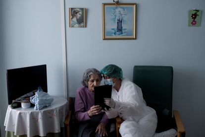 Una persona mayor y una enfermera delante de una pantalla en la residencia de Celanova (Ourense).