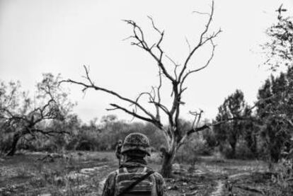 En esta página, fachada de una casa derruida junto al río. El teniente Casas dice que hace unos días había ahí gente de fiesta con coches nuevos y whisky caro. A la derecha, un militar de patrulla. Todos llevan casco, chaleco y fusil FX de calibre 5.56.