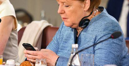 La canciller alemana, Angela Merkel, consulta su m&oacute;vil en un desayuno de trabajo del Consejo Asesor de Igualdad de G&eacute;nero en la cumbre del G7 celebrada el 8 de junio de 2018 en Quebec, Canada.