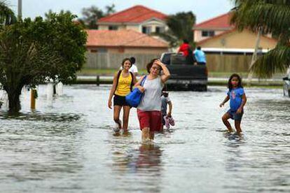 Un grupo de personas camina por una calle inundada de Miami Dade.